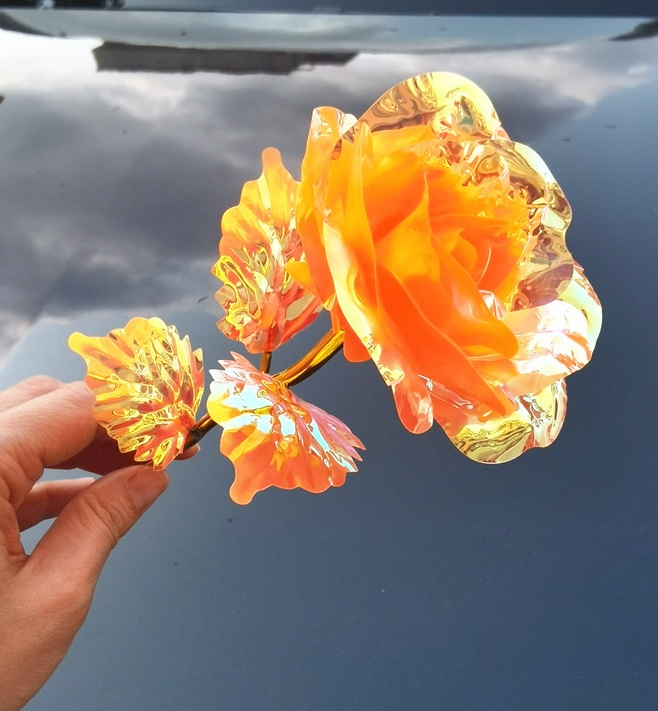 Decorative orange flower with gold dipped stem. Plastic.