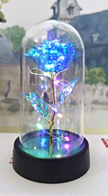 Decorative LED rose in a glass dome on a table with a blurred background