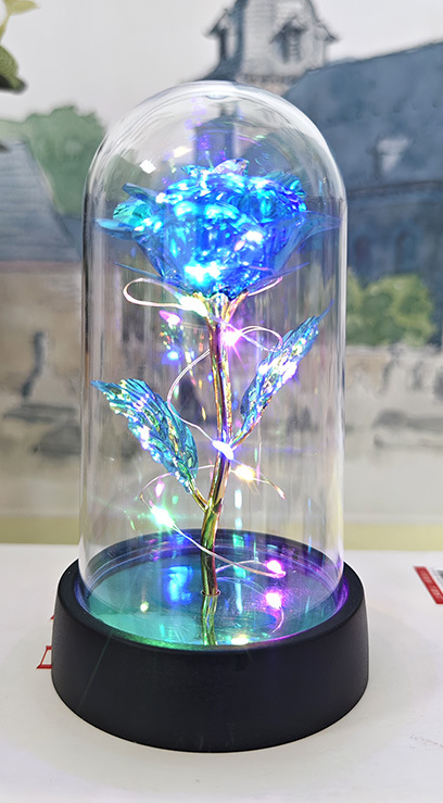 Decorative LED rose in a glass dome on a table with a blurred background