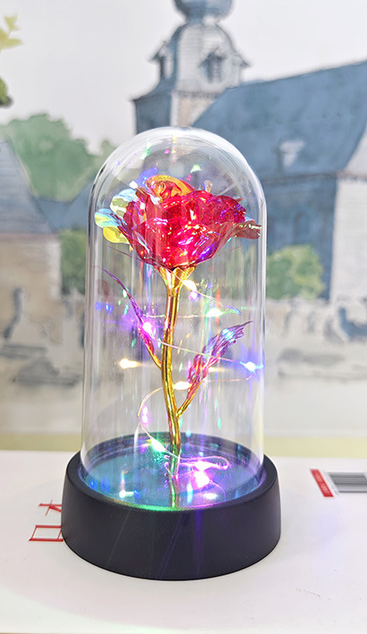 Decorative flower in a glass dome on a black base with a blurred background