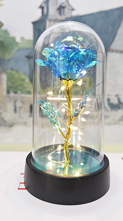 Decorative rose in a glass dome with a black base on a white surface.