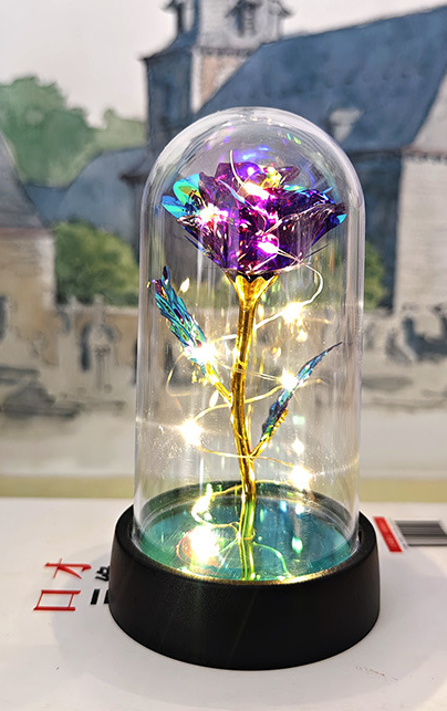 Decorative item with a colorful rose inside a glass dome on a blurred background