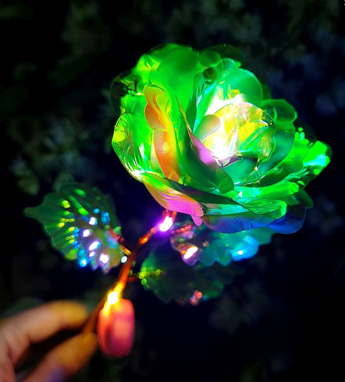 Colorful LED flower being lit with a match against a dark background