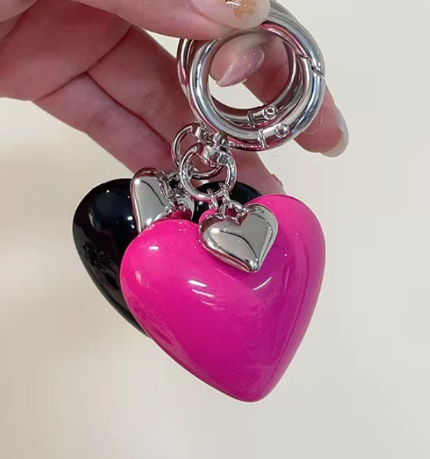 Heart-shaped keychain with a pink heart and silver charm.